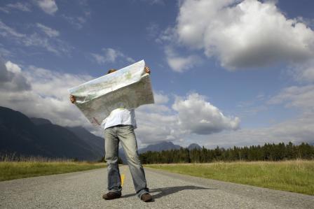 man_standing_on_rural_road_holding_map