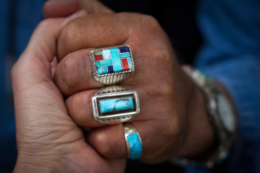 A close-up shot of Native American turquoise rings on a man’s hand.